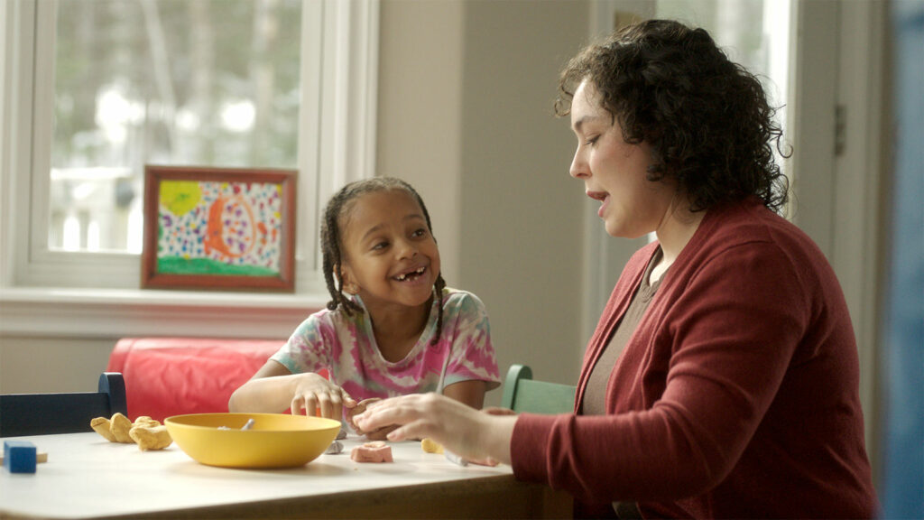 Child and caregiver playing with clay.
