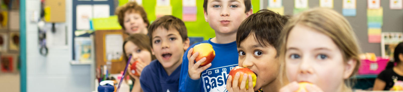 Children in a classroom having a snack of apples.