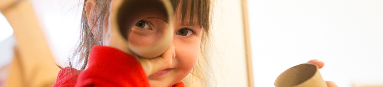 Girl playing with cardboard tubes